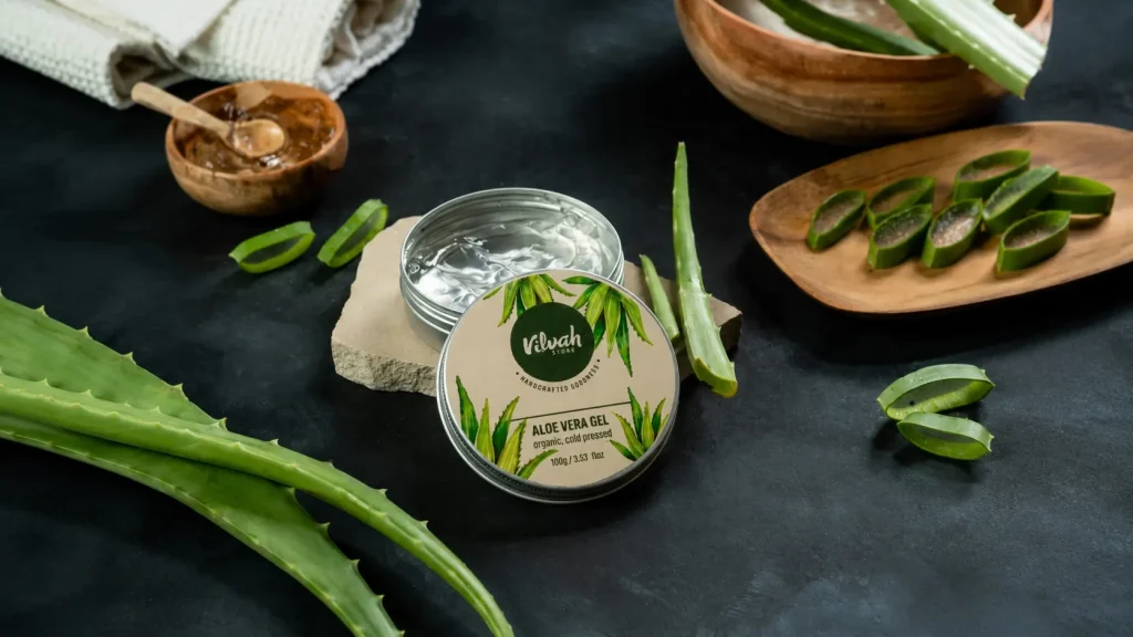 Natural aloe vera gel in a container with fresh aloe vera leaves for skincare and skin hydration
