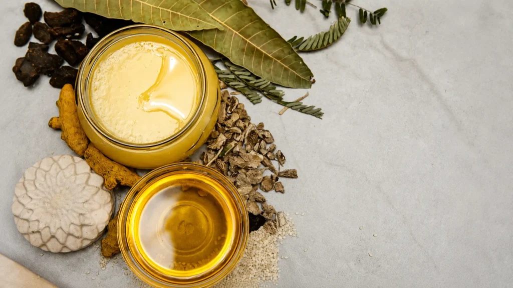 Ingredients for making natural ayurvedic face cream at home including herbal oils, turmeric, and dried herbs