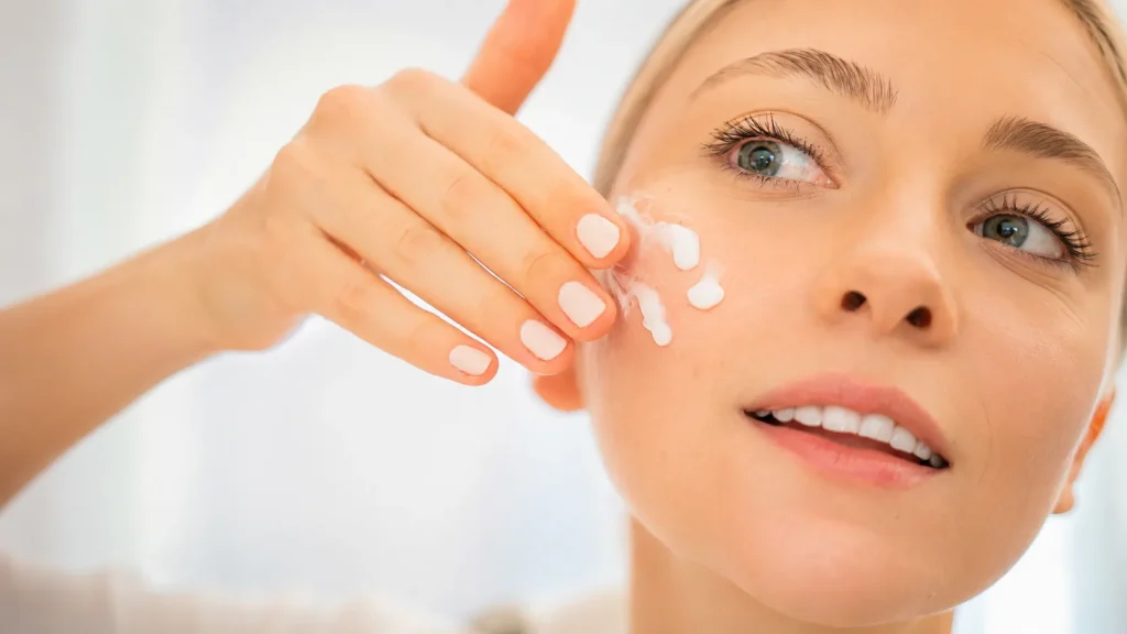 Woman applying tallow face cream to her cheek as part of a natural skincare routine for hydrated and healthy-looking skin.