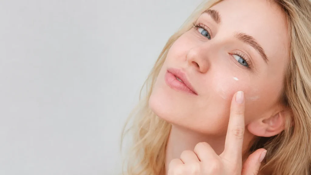 Woman applying estradiol cream to her face for healthy, hydrated skin.